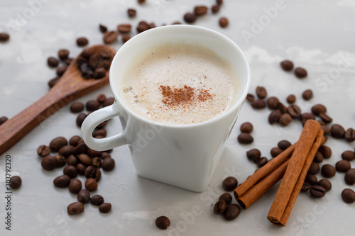 a cup of coffee with milk and grains on ceramic background
