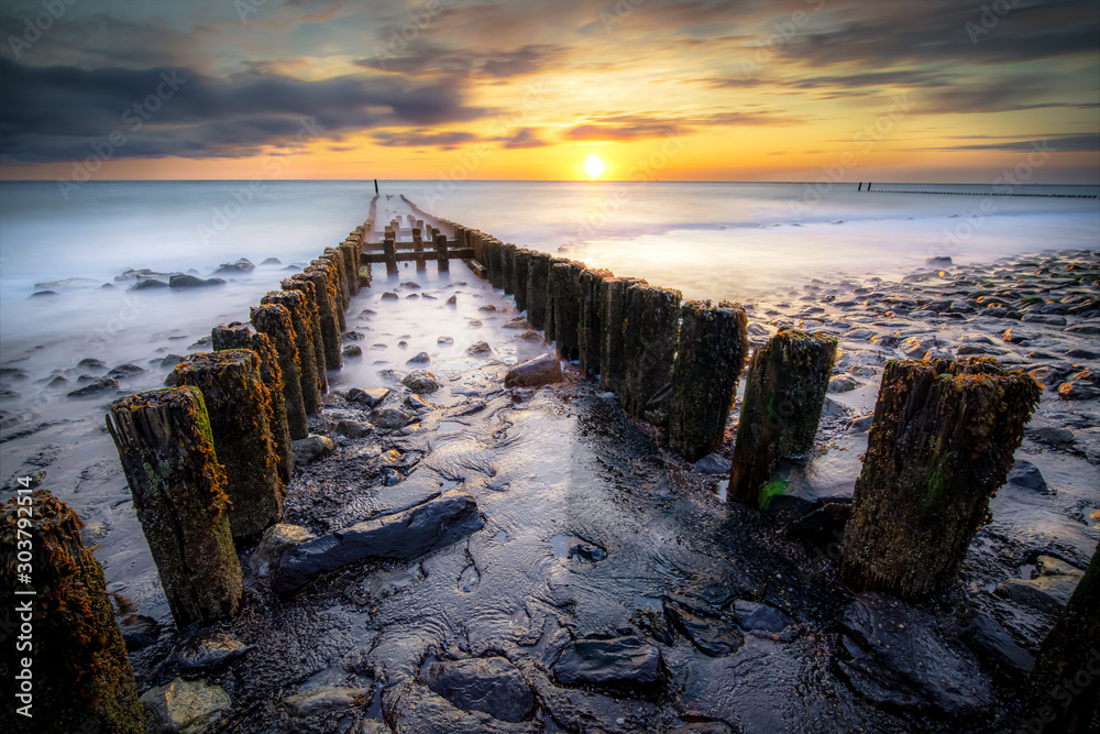 Φωτογραφία Long exposure photo of a wooden wavebreaker in the evening.