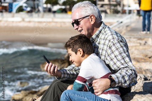 Sticker Grandpa and grandson with a mobile near the sea
