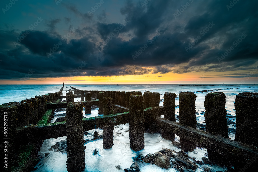 Long exposure photo of a wooden wavebreaker in the evening.