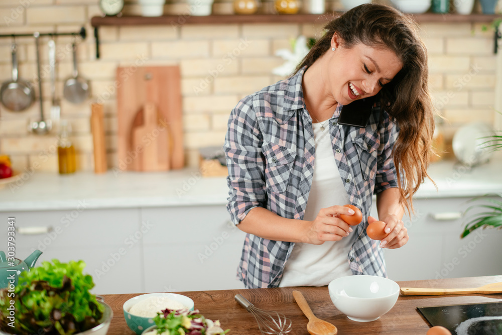 Young woman in kitchen. Beautiful woman taking on phone while cooking. Young woman in kitchen. Beautiful woman taking on phone while cooking.