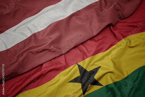 waving colorful flag of ghana and national flag of latvia.