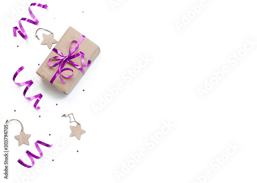 minimalistic christmas composition. Wrapped gift with a violet bow  on a white background decorations, wrapping ribbon, sparkles stars. top view, copy space, happy new year concept