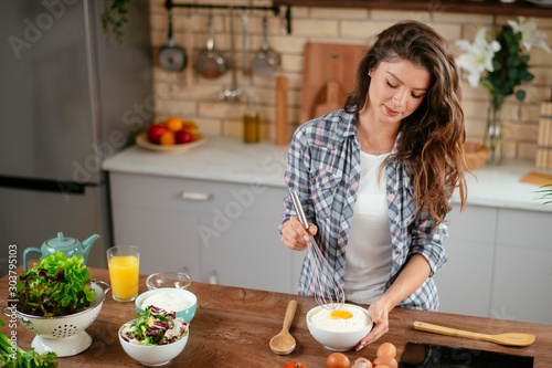 Young woman in kitchen. Beautiful woman making cookies.