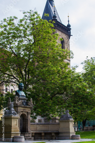 Vertical picture of the Vítězslav Hálek Memorial, an outdoor monument to Vítězslav Hálek in Charles Square, with the New Town Hall (Novoměstská radnice) at the background in Prague, Czech Republic photo