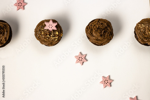 Chocolate homemade cupcakes with chocolate icing and decorated with pink snowflakes photo