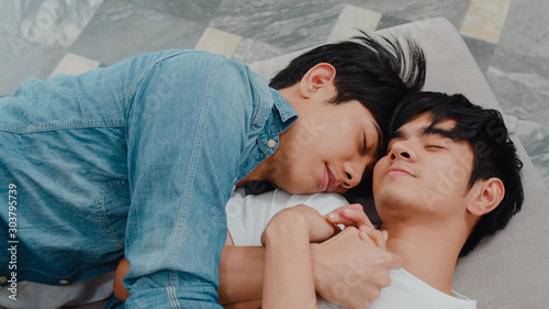 Young Asian gay couple sleep together at home. Teen korean LGBTQ+ men happy relax rest lying on bed in bedroom at house in the morning. photo