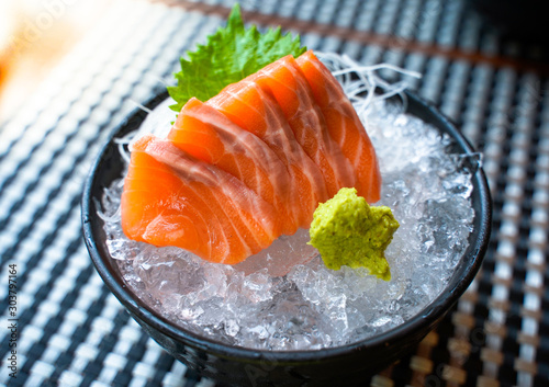 Close up Japanese salmon sashimi on top of wasabi in ice bowl put on dish pad in Japanese restaurant.