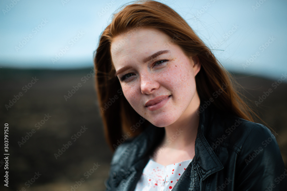 The red-haired girl smiles slyly at the camera and slightly squints The red-haired girl smiles slyly at the camera and slightly squints