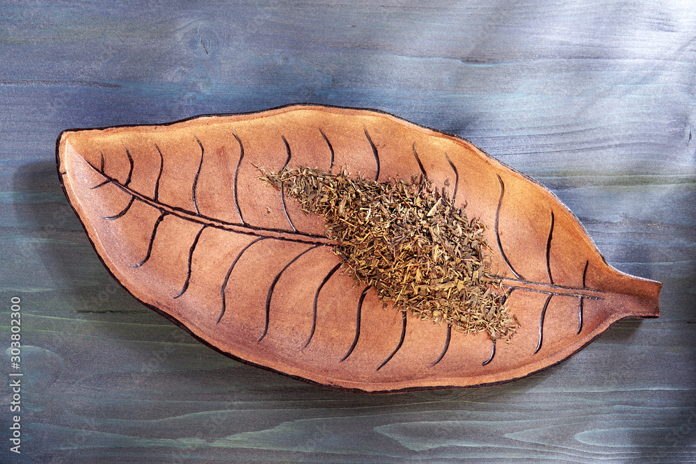 Φωτογραφία Traditional South American Yerba Mate tea on vintage wooden leaf form plate with shadows of plants