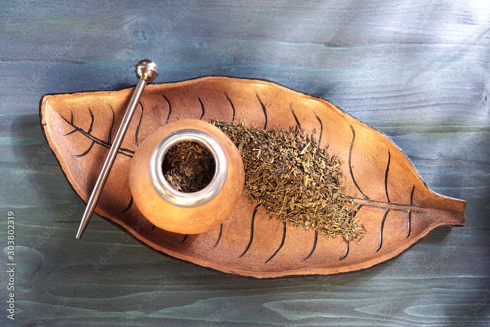 Φωτογραφία Traditional South American Yerba Mate tea in wooden mate cup - calabash with bombilla metal straw on vintage wooden leaf form plate