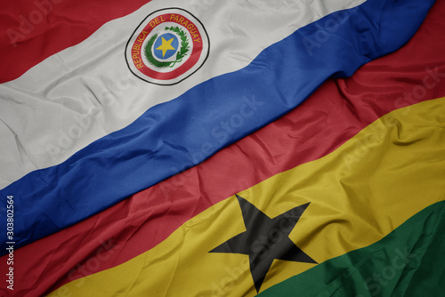 waving colorful flag of ghana and national flag of paraguay.