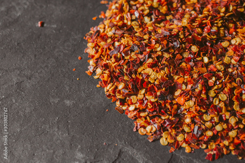 Close up view of red chili flakes on black slate background. Crushed red cayenne pepper. 