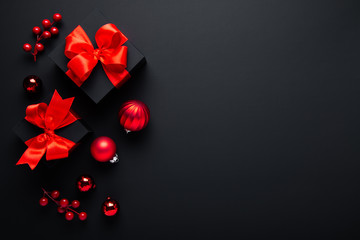 Merry Christmas and Happy Holidays greeting card, banner. New Year. Noel. Christmas red ornaments and gifts on black background top view. Winter xmas holiday theme.