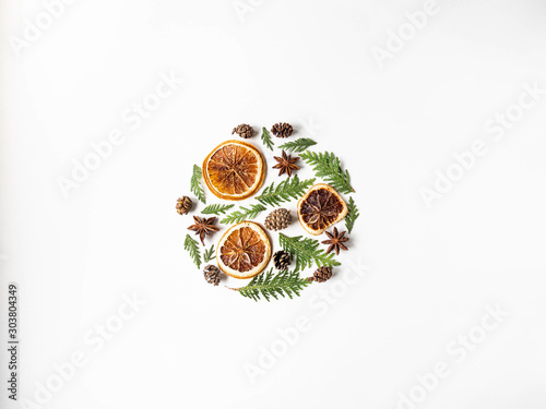 Flat lay creative natural layout circle of plants and spices. Thuja, cones, dry orange slices, spices on white background. Copy space, top view