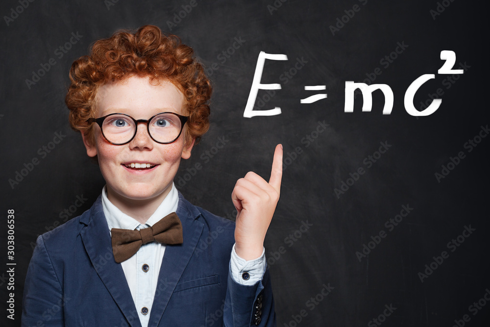 Little schoolboy in glasses on blackboard background portrait