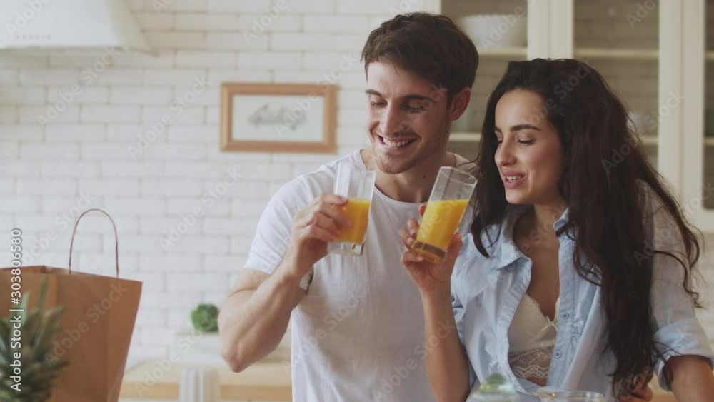 Happy couple drinking orange juice at kitchen. Closeup couple flirting at home. Happy couple drinking orange juice at kitchen. Closeup couple flirting at home.