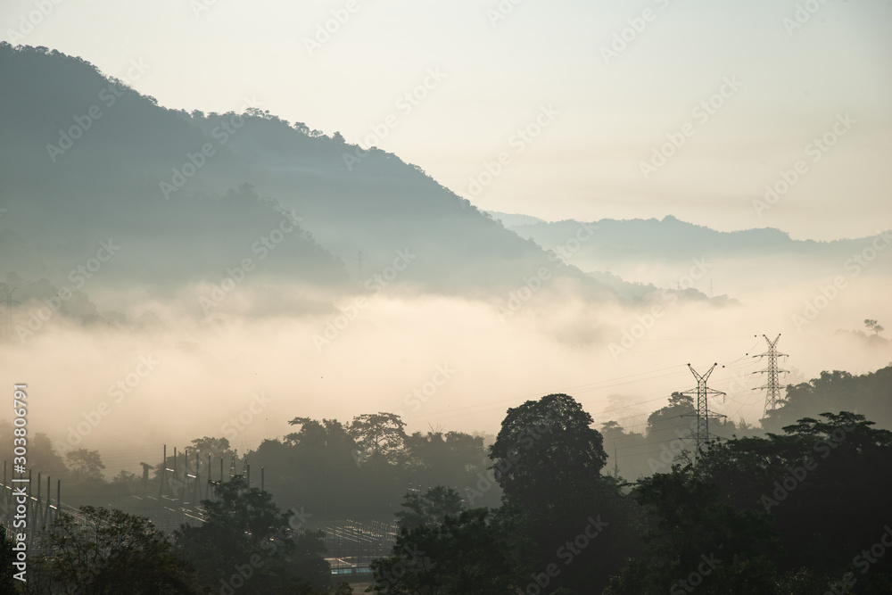 Fototapeta premium yellow bright multi layer mountain and high voltage power line in morning view with mist