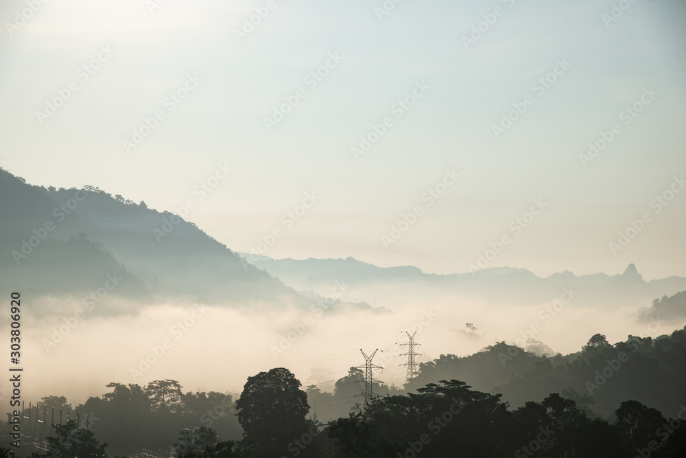 yellow bright multi layer mountain and high voltage power line in morning view with mist
