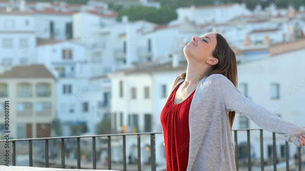 Relaxed woman breathing deep fresh air standing in a balcony in a rural town Relaxed woman breathing deep fresh air standing in a balcony in a rural town