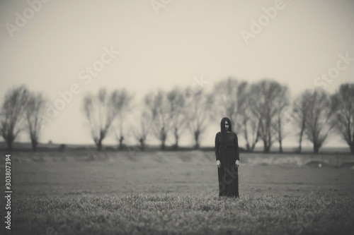 Girl in a long dress on the background of a gloomy forest black and white photo . A woman in a dark forest scary atmosphere like in a horror movie. An image of a girl from a Halloween horror movie. photo