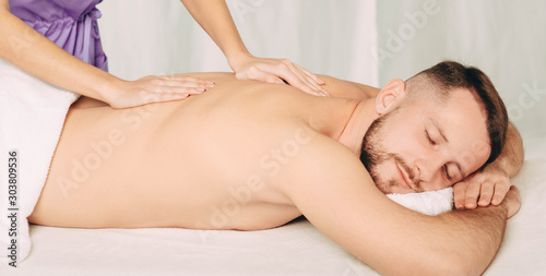 Handsome man enjoying back massage at spa resort