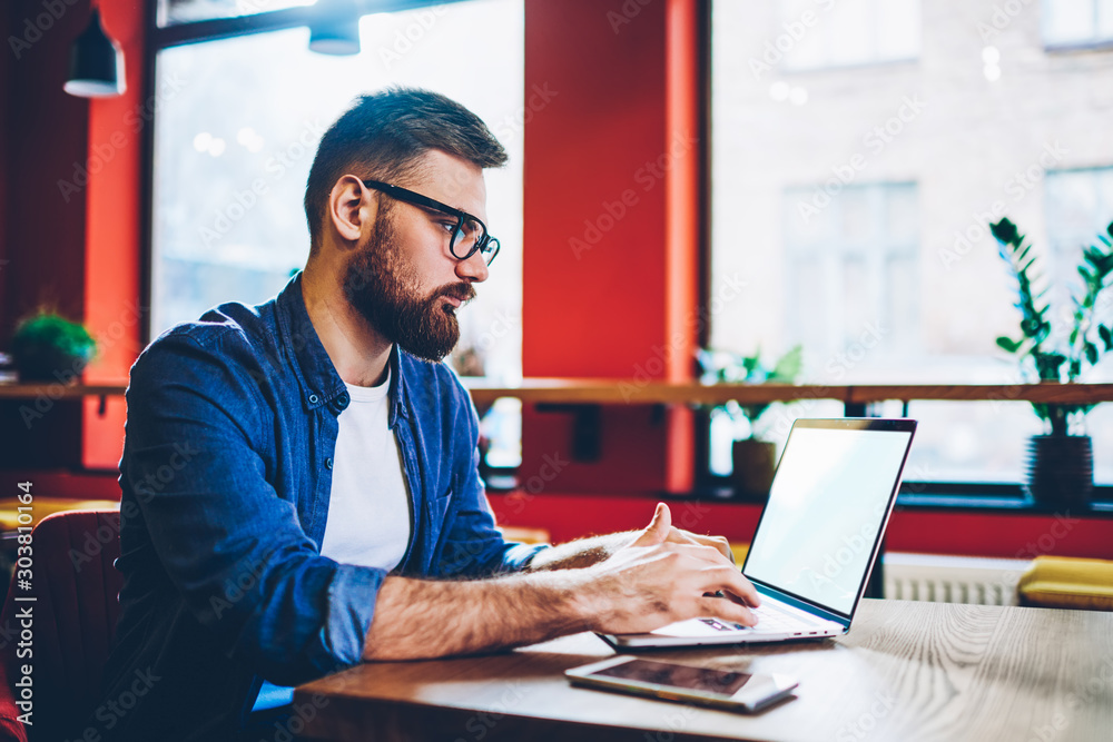 Fototapeta premium Skilled hipster guy working remotely with startup project on laptop device with copy space area for internet websites connected to 4g wireless for browsing web pages,concept of distance job