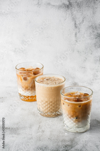 Three glasses with cold brew coffee and milk and ice cocoa isolated on bright marble background. Overhead view, copy space. Advertising for cafe menu. Coffee shop menu. Horizontal photo.