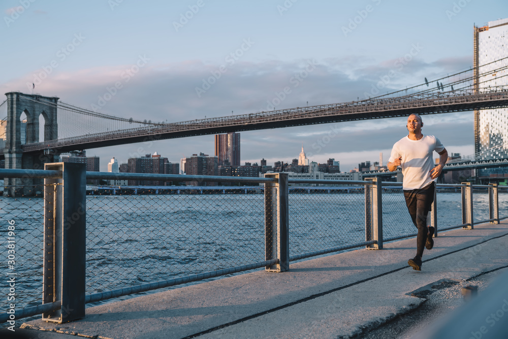 Sportsman running along embankment in city