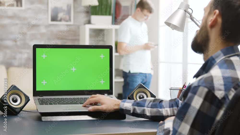 Over the shoulder parallax shot of man working on laptop with green screen Over the shoulder parallax shot of man working on laptop with green screen
