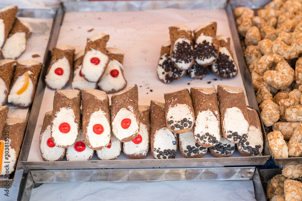 Freshly made sicilian Cannoli on a shelf in an outdoor market. They are a typical local sweet of the island.,street food.