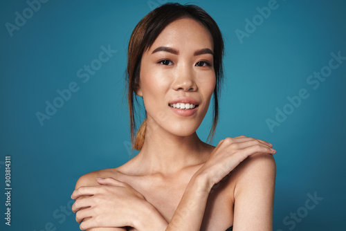Positive smiling asian woman posing naked isolated