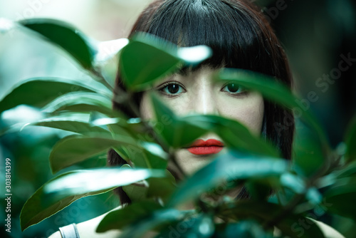 Bbeautiful girl stand behind a tree leaves photo