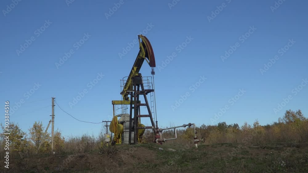 Oil well extraction pump in the wood. Mechanism operation, close-up Oil well extraction pump in the wood. Mechanism operation, close-up