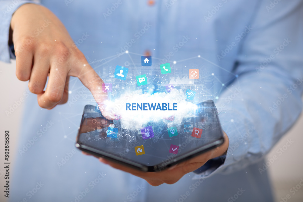 Businessman holding a foldable smartphone with RENEWABLE inscription, technology concept Businessman holding a foldable smartphone with RENEWABLE inscription, technology concept