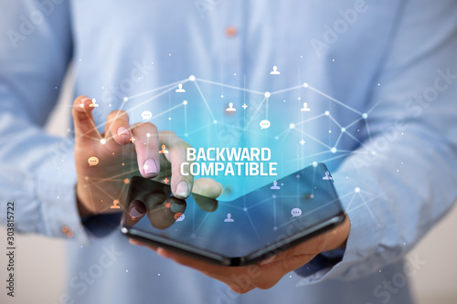 Businessman holding a foldable smartphone with BACKWARD COMPATIBLE inscription  new technology concept