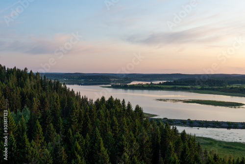 View from the mountain to the coniferous forest and lake. Sunset on Mount Paaso. Karelia