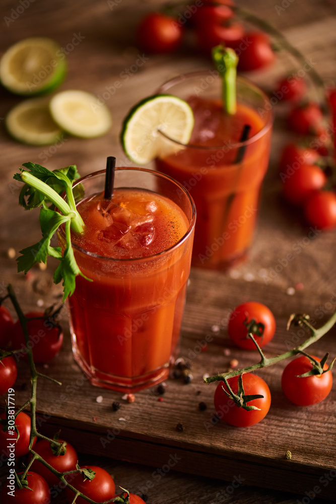 selective focus of bloody mary cocktail in glasses on wooden background with salt, pepper, tomatoes and celery selective focus of bloody mary cocktail in glasses on wooden background with salt, pepper, tomatoes and celery