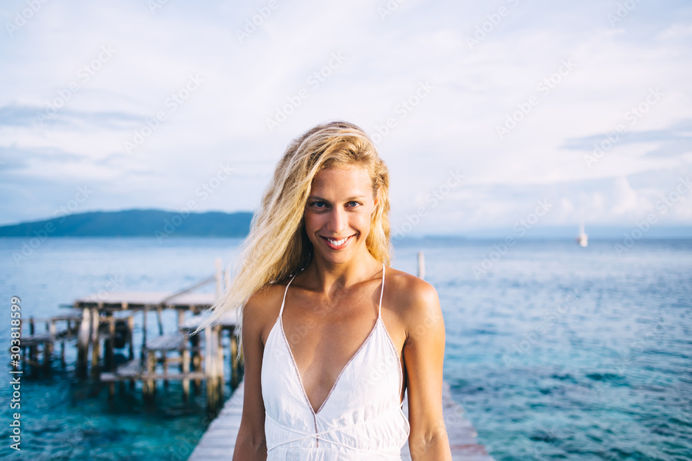 Happy slim female in light dress standing on boardwalk Happy slim female in light dress standing on boardwalk