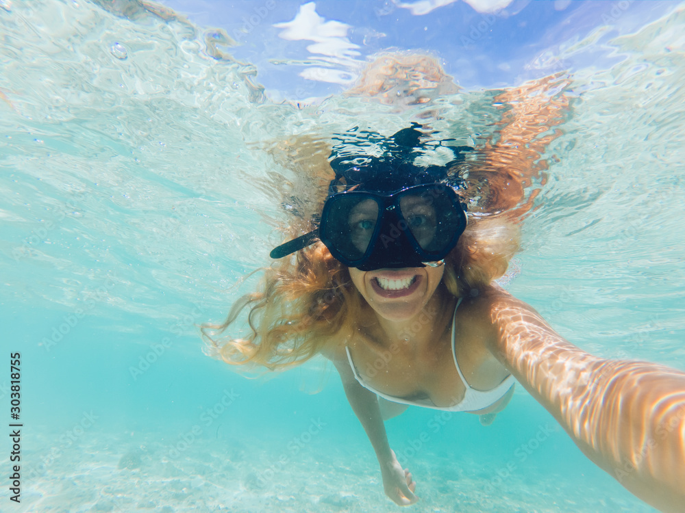 Young smiling blonde taking selfie underwater