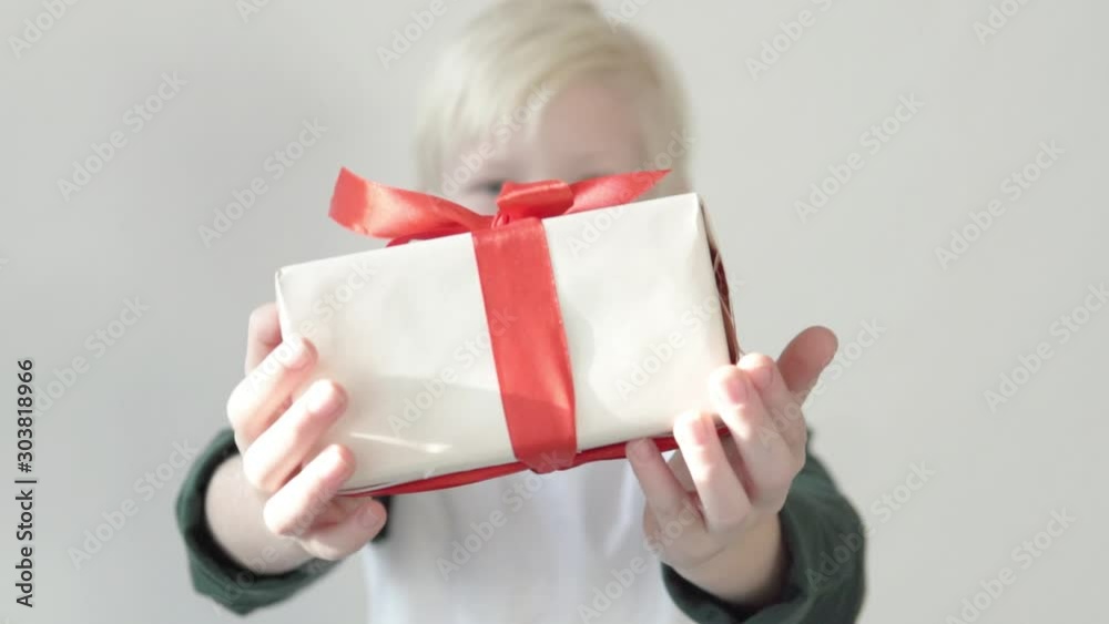 blond boy holds out a beautifully wrapped present to the camera. Focus on the gift. Slow motion blond boy holds out a beautifully wrapped present to the camera. Focus on the gift. Slow motion