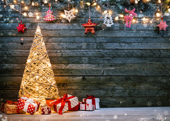 Holidays background with illuminated Christmas tree, gifts and decoration.