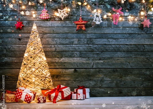 Holidays background with illuminated Christmas tree, gifts and decoration.