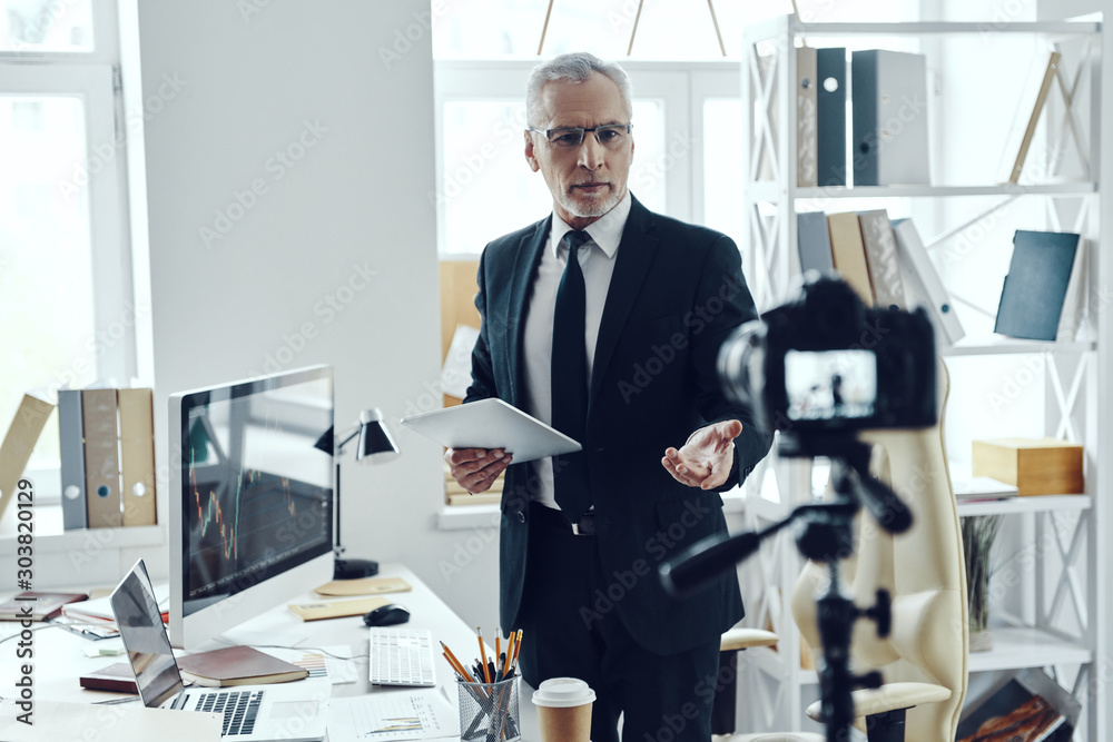 Fototapeta premium Senior man in elegant business suit sharing his business experience while making social media video