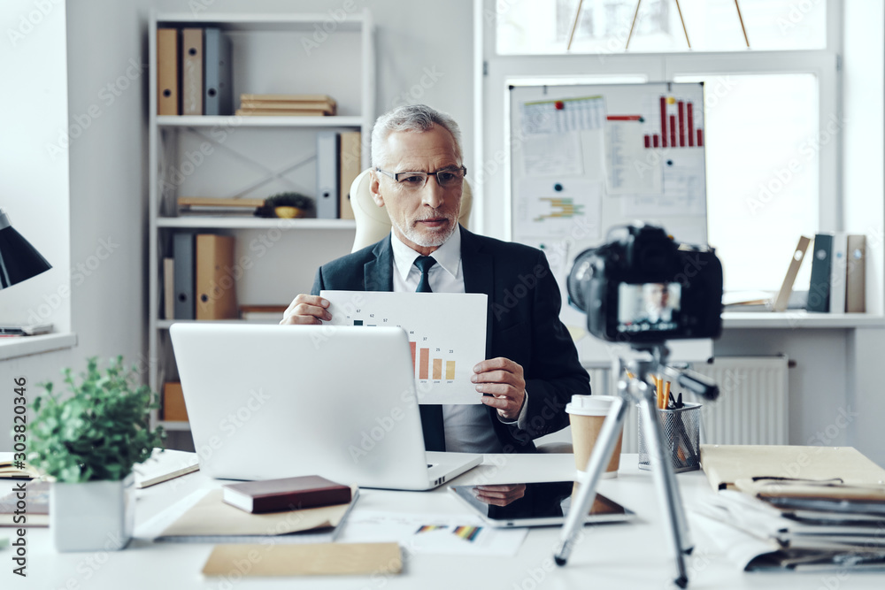 Fototapeta premium Senior man in elegant business suit showing chart while making social media video