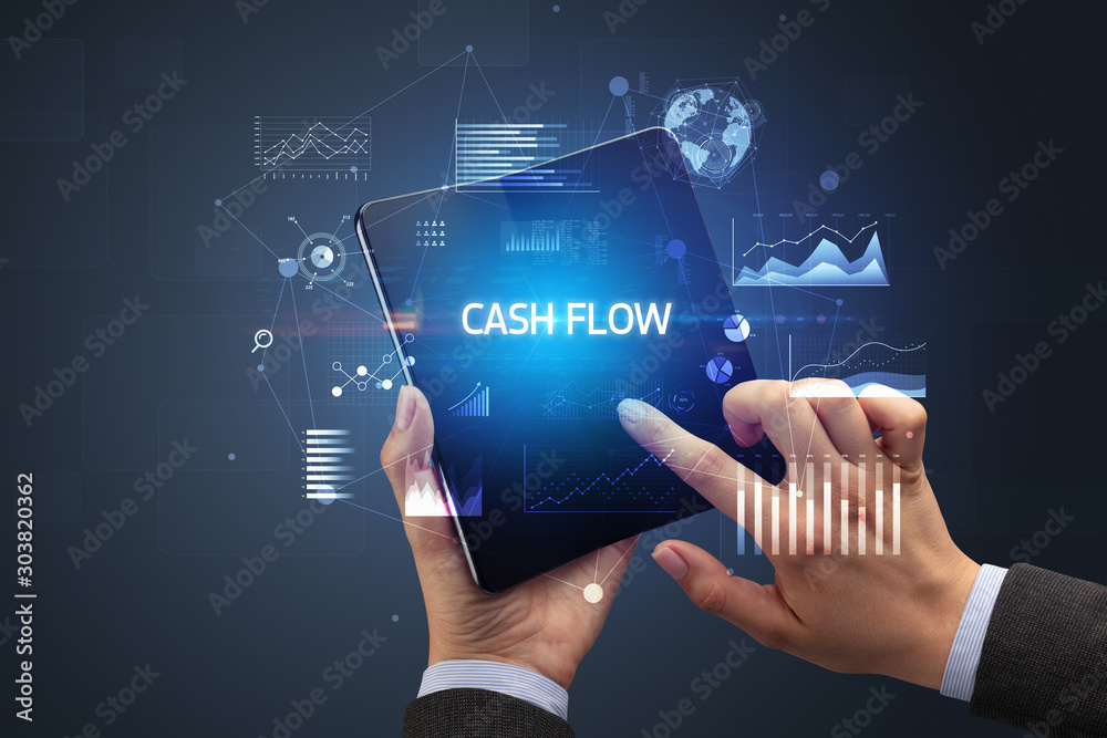Businessman holding a foldable smartphone with CASH FLOW inscription, successful business concept Businessman holding a foldable smartphone with CASH FLOW inscription, successful business concept