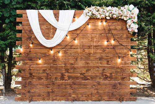 Rustic wooden wedding arch with retro garland decorated with flowers for wedding ceremony newlyweds