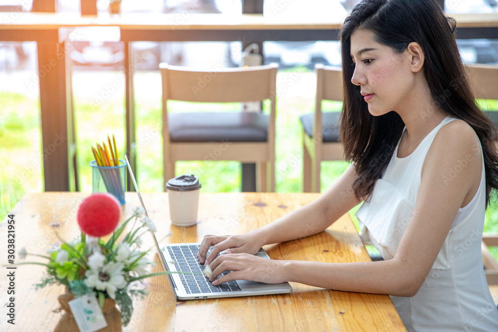 Portrait of a young female freelancer using laptop computer for distance job while sitting in modern coffee shop interior, Portrait of a young female freelancer using laptop computer for distance job while sitting in modern coffee shop interior,