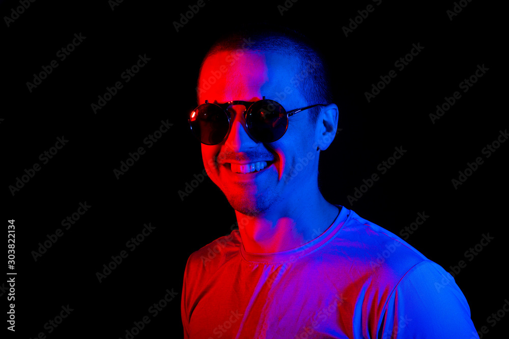 Man smiling and looking in camera in sunglasses with color blue and red light