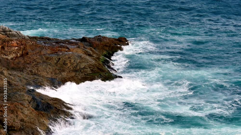 Rolling waves splash up onto a rocky point during a windy day on the coast Rolling waves splash up onto a rocky point during a windy day on the coast
